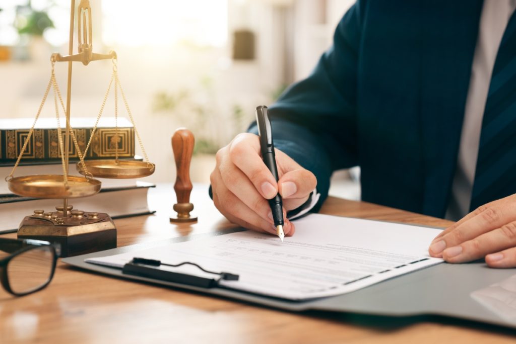 Legal professional writing on some papers on his office table