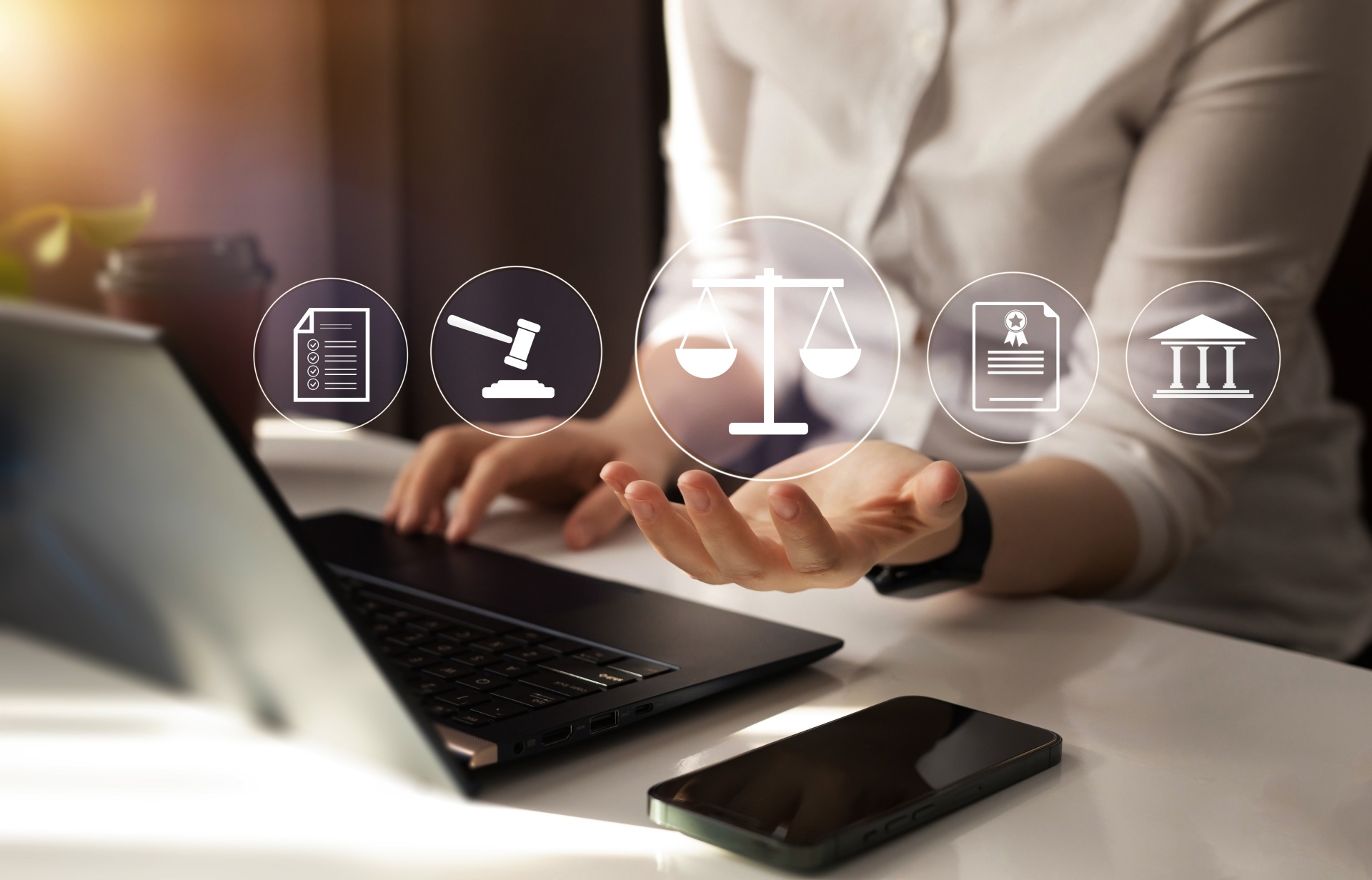 Person working on laptop with signs of the legal system appearing virtually on the image