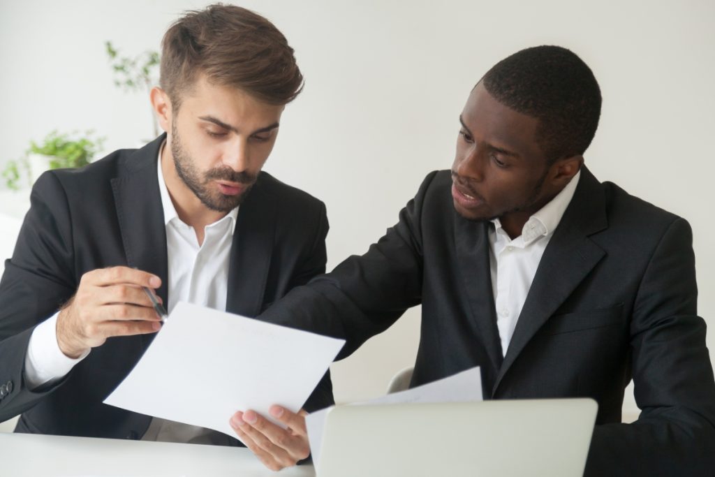 2 professionals in discussion with each other while working on some papers and projects